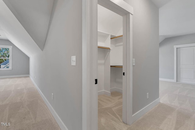 corridor with light colored carpet and vaulted ceiling