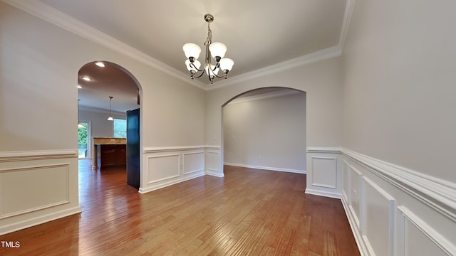 unfurnished room featuring crown molding, a chandelier, and light hardwood / wood-style floors