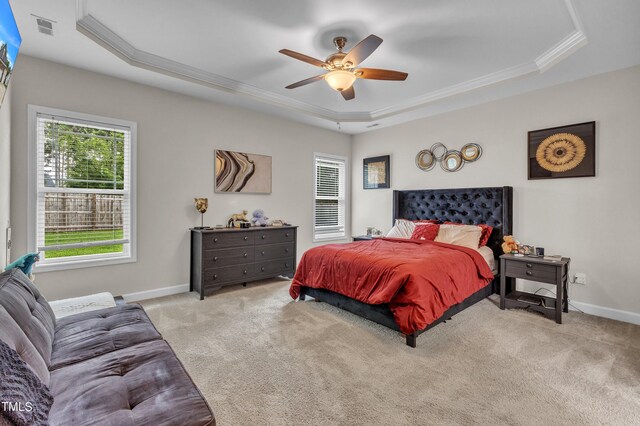 bedroom with ceiling fan, light colored carpet, and a tray ceiling