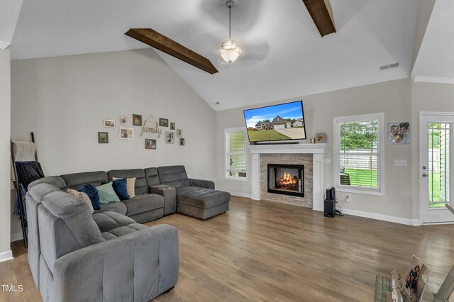 living room featuring beam ceiling, wood-type flooring, a fireplace, and ceiling fan