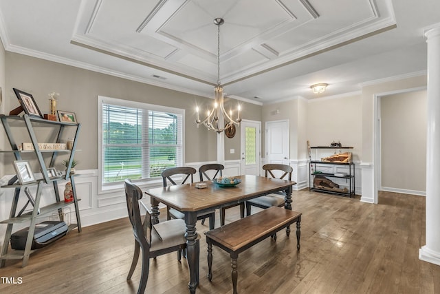 dining area with crown molding, a raised ceiling, hardwood / wood-style floors, and a chandelier