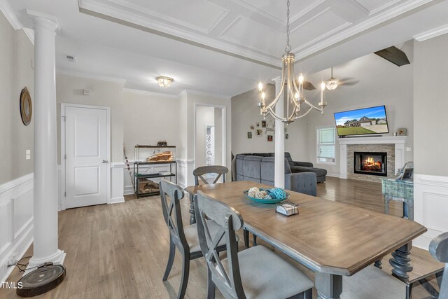 dining area with a chandelier, ornate columns, a fireplace, light hardwood / wood-style floors, and ornamental molding