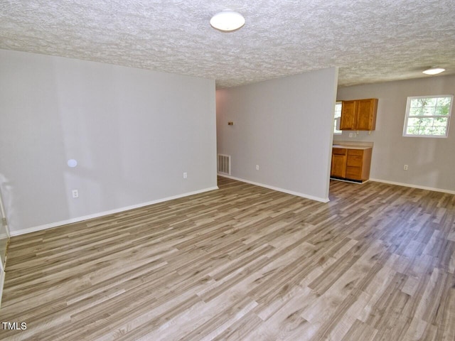 unfurnished living room featuring light wood-type flooring and a textured ceiling