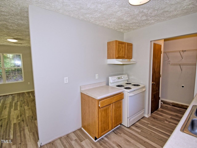 kitchen featuring sink, white electric range oven, light hardwood / wood-style flooring, and a textured ceiling