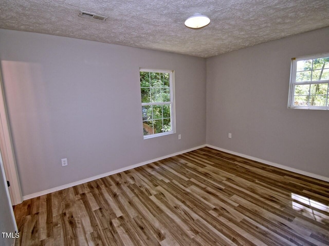 empty room with a textured ceiling and wood-type flooring