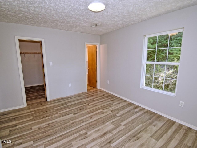 interior space with multiple windows, a closet, a spacious closet, and light hardwood / wood-style flooring