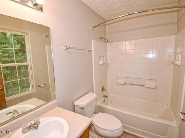 full bathroom featuring a textured ceiling, vanity, tiled shower / bath combo, and toilet