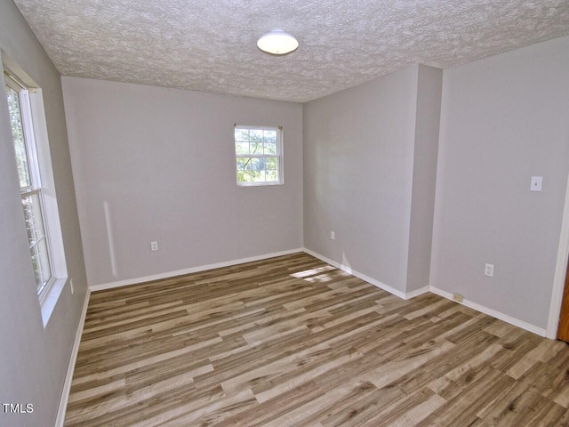 unfurnished room with hardwood / wood-style flooring and a textured ceiling