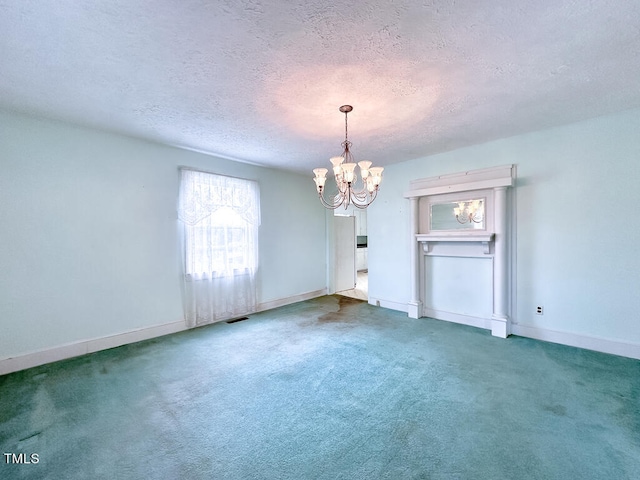 carpeted empty room featuring a textured ceiling and a chandelier