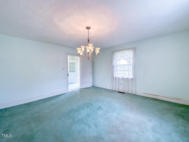 carpeted spare room featuring a notable chandelier and a textured ceiling