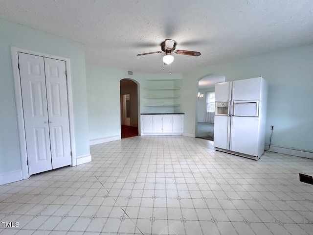 interior space with ceiling fan, light tile patterned floors, a textured ceiling, and built in features