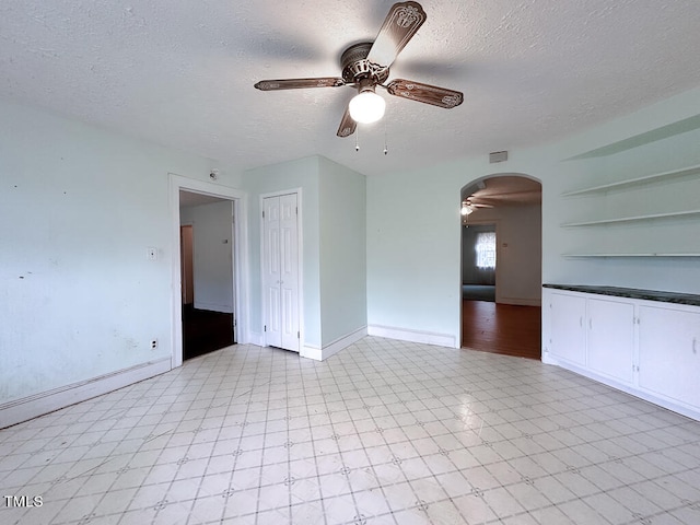 tiled spare room featuring ceiling fan, baseboard heating, and a textured ceiling