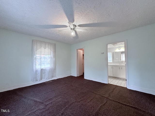 empty room featuring ceiling fan, light tile patterned flooring, a wealth of natural light, and a textured ceiling