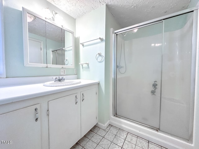 bathroom featuring an enclosed shower, vanity, a textured ceiling, and tile patterned flooring