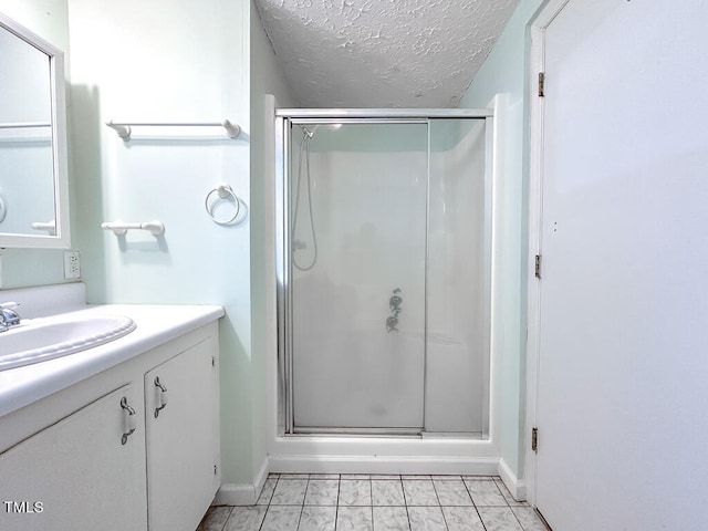 bathroom with a shower with shower door, a textured ceiling, vanity, and tile patterned flooring