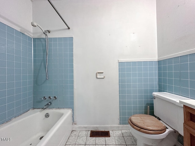 full bathroom with toilet, tile patterned floors, tiled shower / bath, tile walls, and vanity