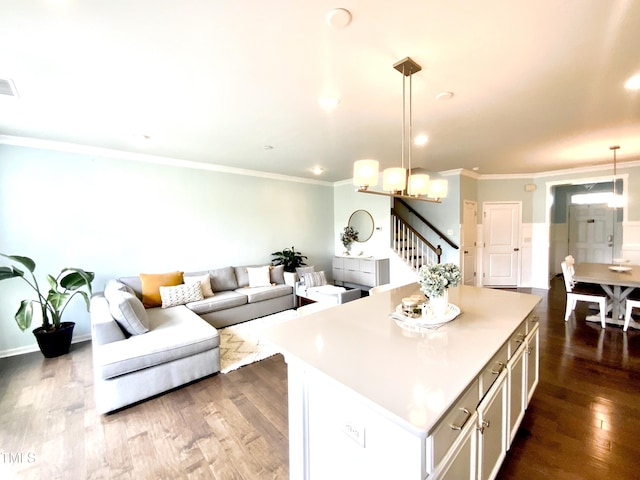 kitchen featuring crown molding, a kitchen island, dark hardwood / wood-style floors, and pendant lighting