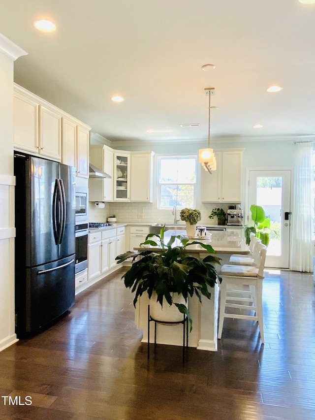 kitchen with a kitchen island, appliances with stainless steel finishes, a breakfast bar, white cabinets, and hanging light fixtures