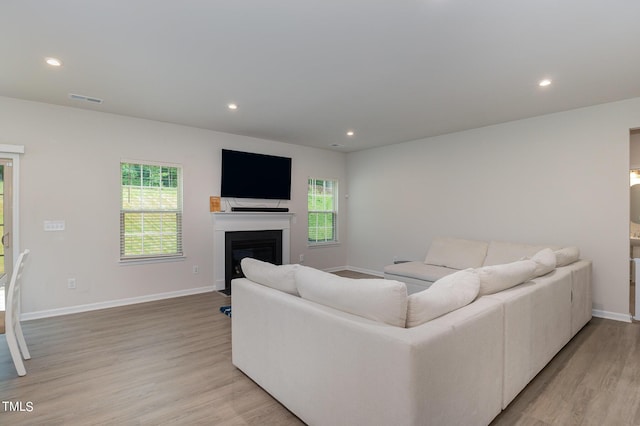 living room featuring light wood-style floors, baseboards, visible vents, and recessed lighting