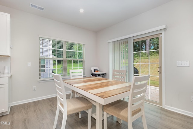 dining space featuring light wood-style flooring, visible vents, and baseboards