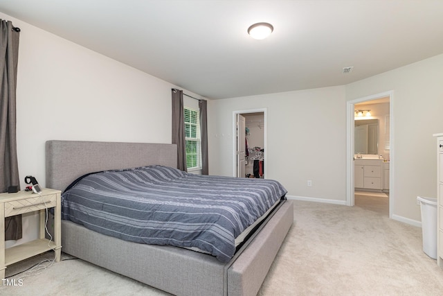 bedroom with connected bathroom, light colored carpet, baseboards, a closet, and a walk in closet