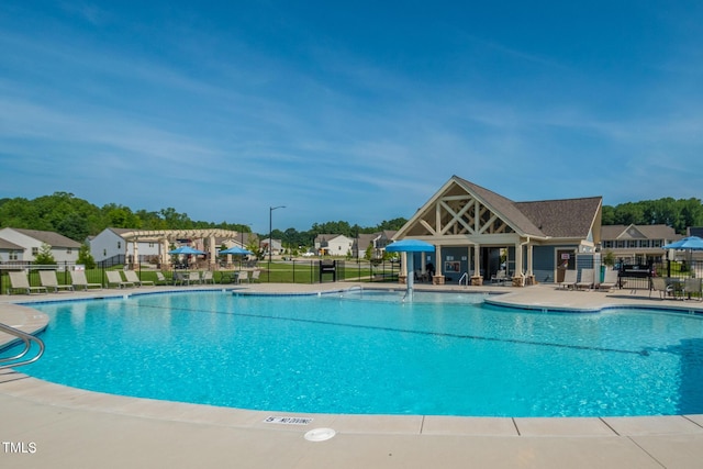 community pool with a patio area and fence