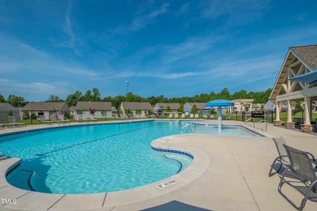 community pool featuring a patio area, fence, and a residential view