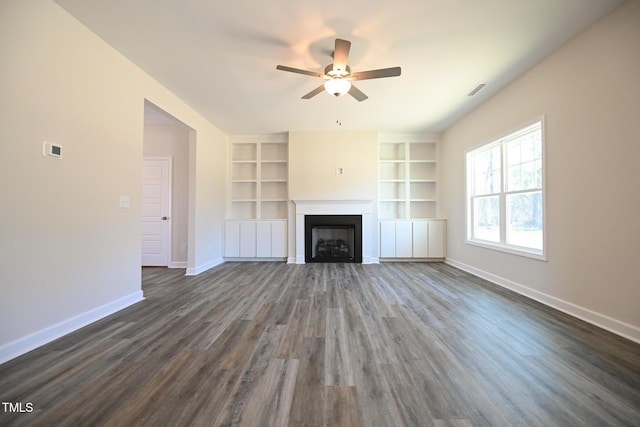 unfurnished living room with dark wood-type flooring, built in features, and ceiling fan