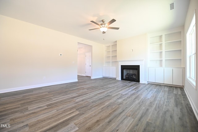 unfurnished living room featuring built in shelves, ceiling fan, and hardwood / wood-style floors