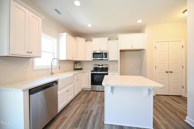 kitchen featuring sink, stainless steel appliances, a center island, and white cabinets