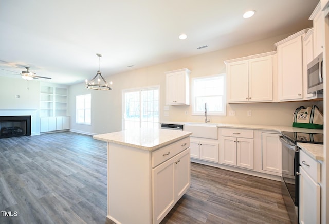 kitchen with sink, white cabinetry, light stone counters, hanging light fixtures, and stainless steel appliances