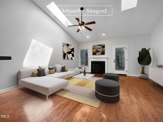 living room featuring high vaulted ceiling, ceiling fan, hardwood / wood-style floors, and a skylight