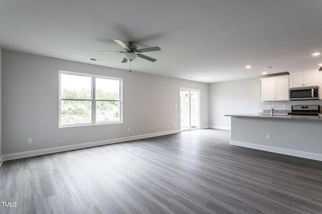 unfurnished living room with ceiling fan, sink, and dark hardwood / wood-style flooring