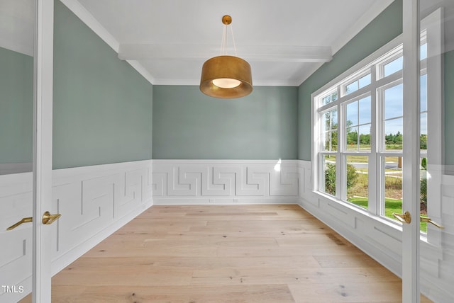 empty room featuring ornamental molding, beamed ceiling, and light hardwood / wood-style flooring