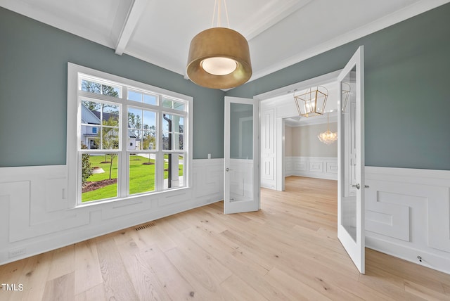 unfurnished dining area with light wood-type flooring, beamed ceiling, french doors, crown molding, and an inviting chandelier