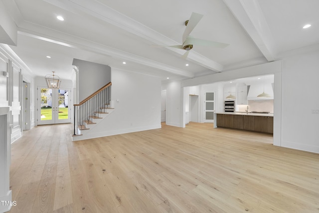 unfurnished living room with french doors, ornamental molding, light hardwood / wood-style flooring, and beam ceiling