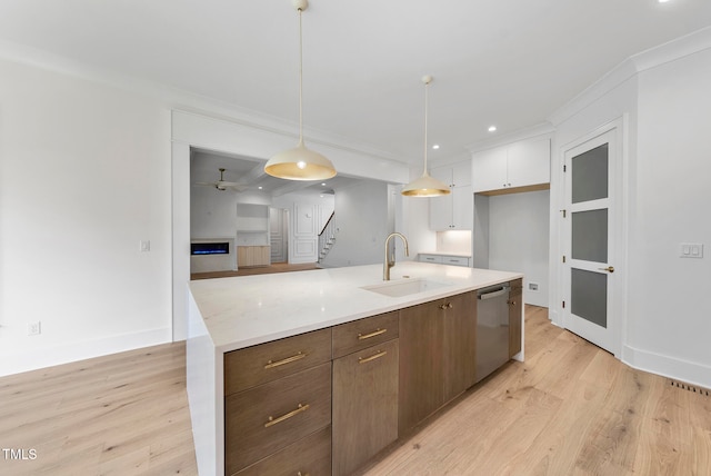 kitchen featuring stainless steel dishwasher, sink, hanging light fixtures, white cabinetry, and light hardwood / wood-style flooring