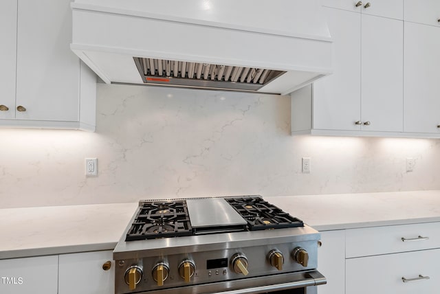 kitchen featuring custom range hood, backsplash, stainless steel stove, and white cabinetry