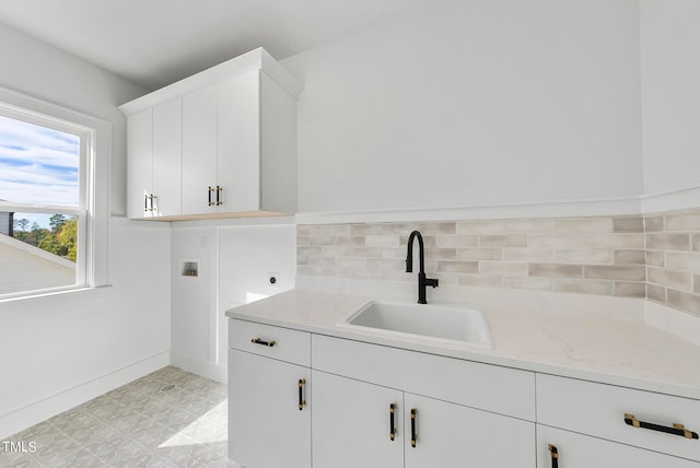 laundry room with cabinets, hookup for an electric dryer, hookup for a washing machine, sink, and light tile patterned floors