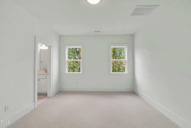 unfurnished bedroom featuring light carpet and ensuite bath