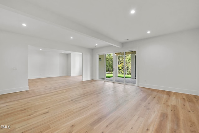 spare room featuring light wood-type flooring and beam ceiling