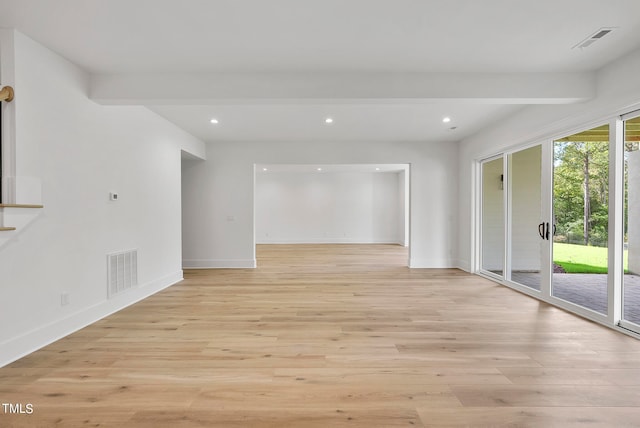 spare room with beam ceiling and light hardwood / wood-style floors