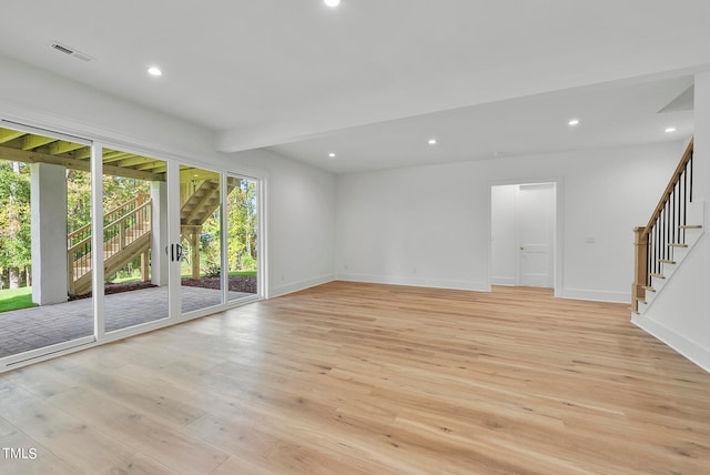 unfurnished living room featuring beamed ceiling and light wood-type flooring