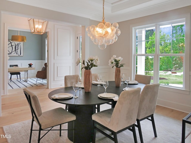 2506 Silas Peak Ln, Apex, NC 27523 - dining space featuring a chandelier, light wood-style floors, a decorative wall, wainscoting, and ornamental molding