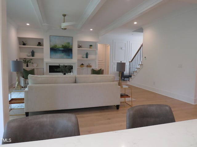 2506 Silas Peak Ln, Apex, NC 27523 - living room with wood finished floors, beam ceiling, ceiling fan, baseboards, and stairs