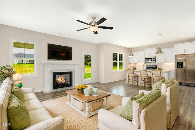 living room with hardwood / wood-style flooring, plenty of natural light, a tile fireplace, and ceiling fan