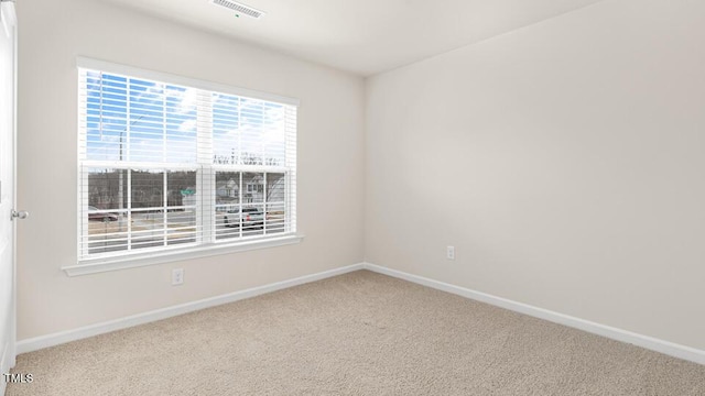 carpeted spare room featuring baseboards and visible vents