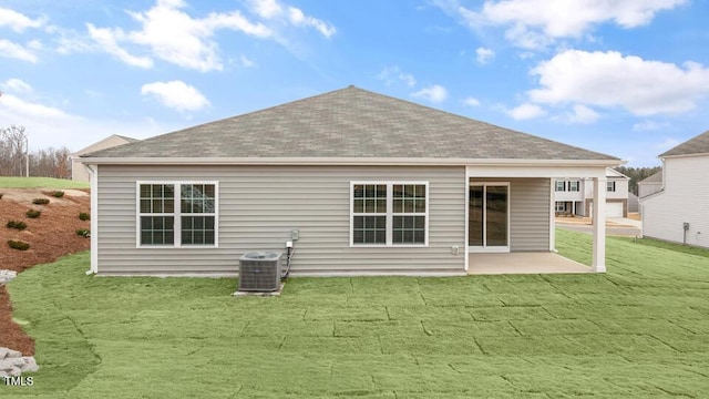 back of property with central AC unit, a lawn, a patio, and a shingled roof