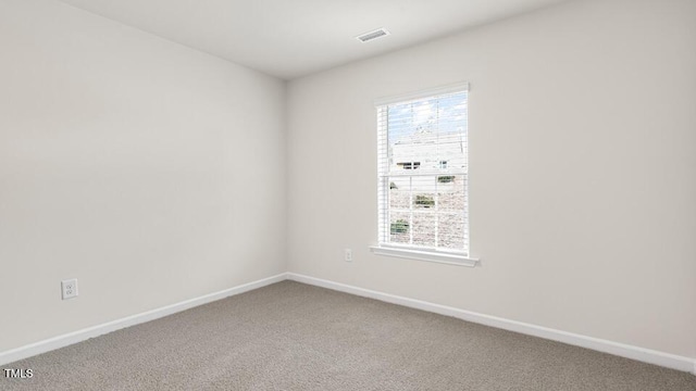 empty room with carpet, visible vents, a wealth of natural light, and baseboards