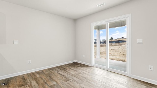 spare room featuring visible vents, baseboards, and wood finished floors